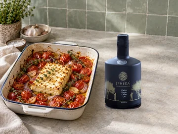 Baked feta with cherry tomatoes, thyme and olive oil, beside the authentic SPHERA bottle in an illustrative recipe scene.